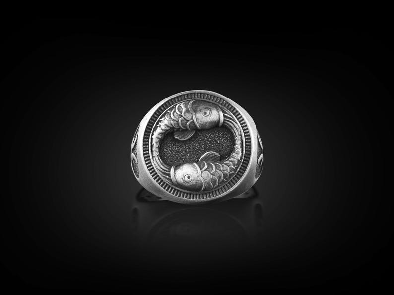 Peut inclure: Une bague en argent avec un motif d&eacute;taill&eacute; de deux poissons se faisant face.