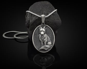 Peut inclure: Un collier en argent avec un pendentif représentant un renard en trois dimensions détaillé. Le renard est assis avec sa queue enroulée autour de son corps. Le pendentif est de forme ovale et a une surface texturée.