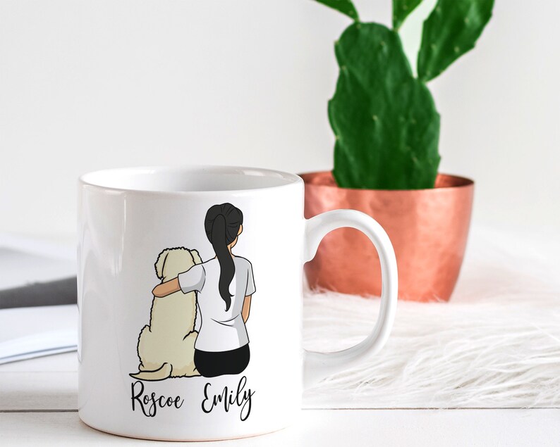 Op de afbeelding: Witte keramische mok met een cartoonillustratie van een vrouw met lang zwart haar en een witte hond. De tekst "Roscoe Emily" staat op de mok gedrukt.