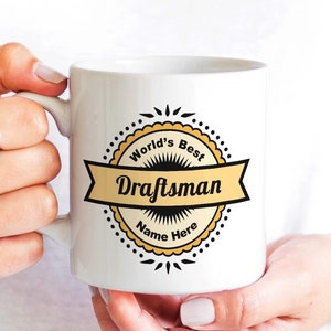 May include: White ceramic mug with a yellow and black design that says "World's Best Draftsman" with a banner and a place to add a name.