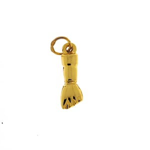 May include: A gold-colored charm in the shape of a hand, with a loop at the top for attaching to a necklace or bracelet. The hand is detailed with lines to represent fingers and is set against a white background.