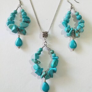 May include: A turquoise gemstone necklace and earrings set. The necklace and earrings feature a silver chain and a teardrop-shaped turquoise gemstone pendant.