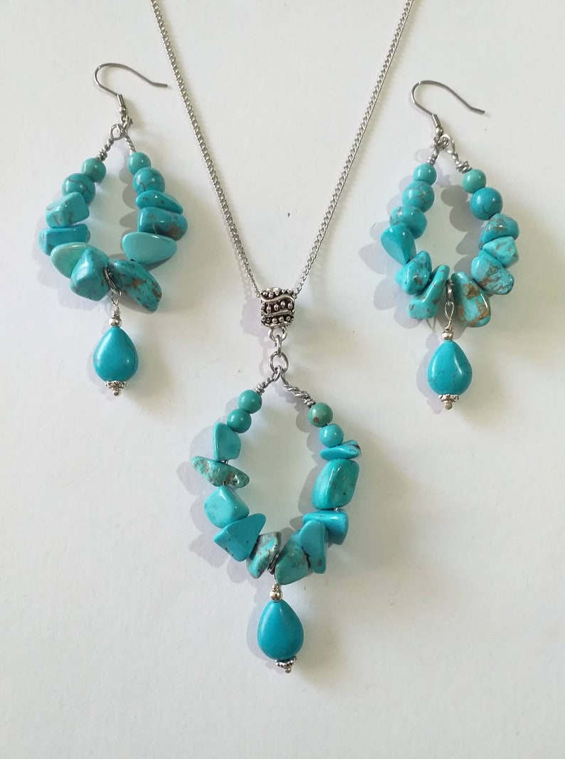 May include: A turquoise gemstone necklace and earrings set. The necklace and earrings feature a silver chain and a teardrop-shaped turquoise gemstone pendant.