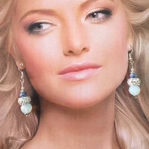 May include: A pair of dangle earrings with a blue and white stone design. The earrings feature a silver tone metal and a light blue stone.