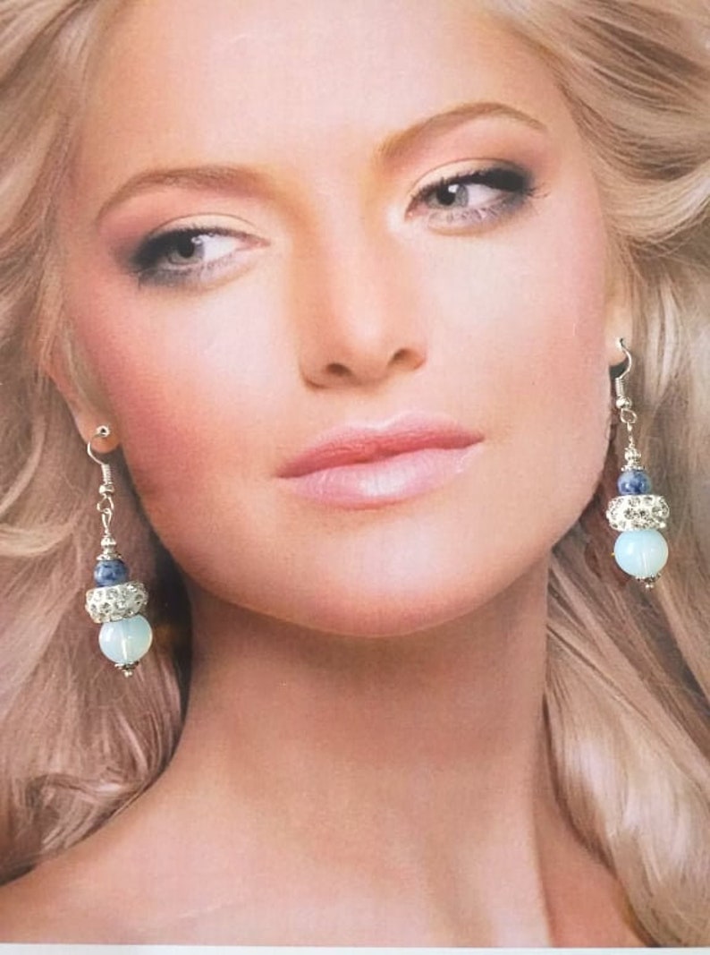 May include: A pair of dangle earrings with a blue and white stone design. The earrings feature a silver tone metal and a light blue stone.