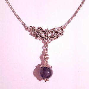 May include: A silver chain necklace with a silver pendant featuring a floral design and a dark purple gemstone.