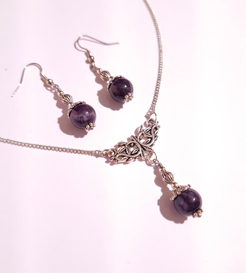 Puede incluir: Un collar de plata con un delicado dise&ntilde;o floral y una piedra de amatista colgante. Incluye pendientes de amatista a juego con ganchos de plata.