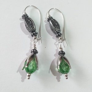 May include: Silver earrings with green crystal flower-shaped beads and silver filigree accents.