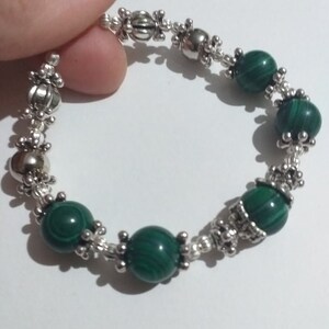 May include: A green malachite stone bracelet with silver beads and decorative accents.