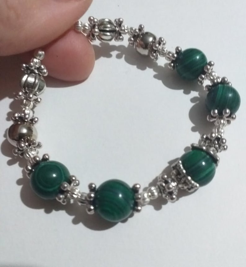 May include: A green malachite stone bracelet with silver beads and decorative accents.