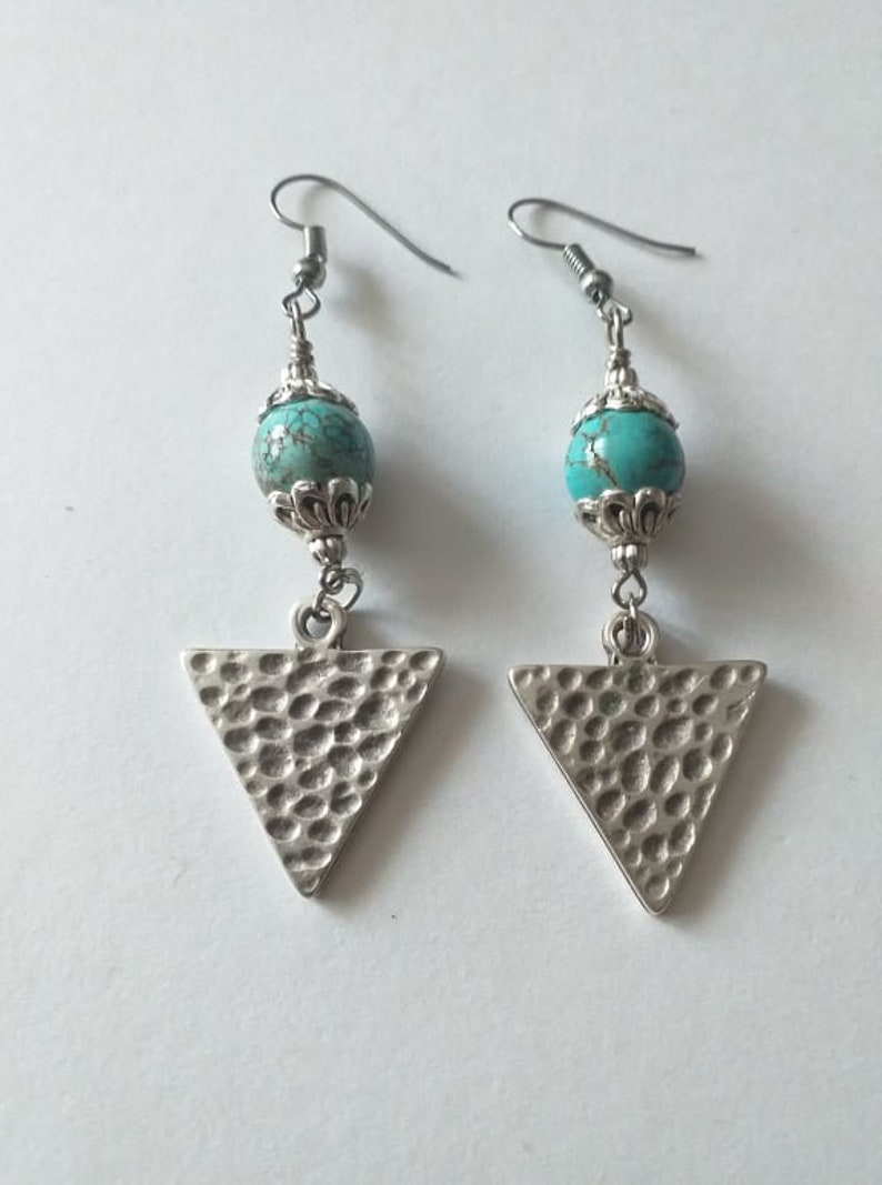 May include: A pair of silver earrings with turquoise beads and triangle pendants. The triangles have a hammered texture.