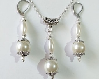 May include: A silver necklace and earrings set with white pearl beads and ornate silver accents.
