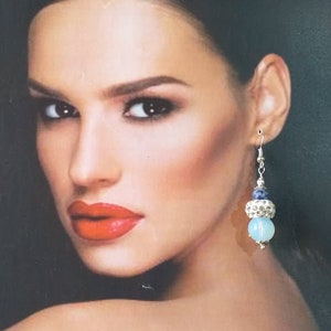 May include: Silver dangle earrings with a blue and white stone bead and a silver bead with rhinestones.