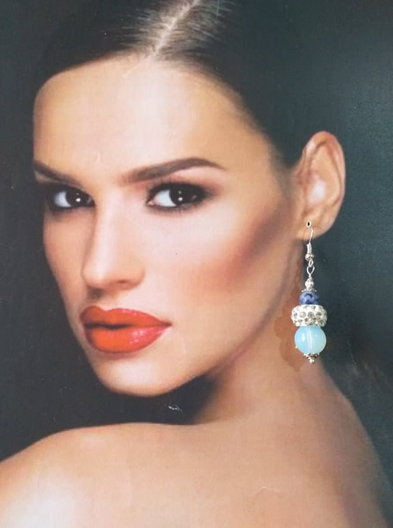 May include: Silver dangle earrings with a blue and white stone bead and a silver bead with rhinestones.