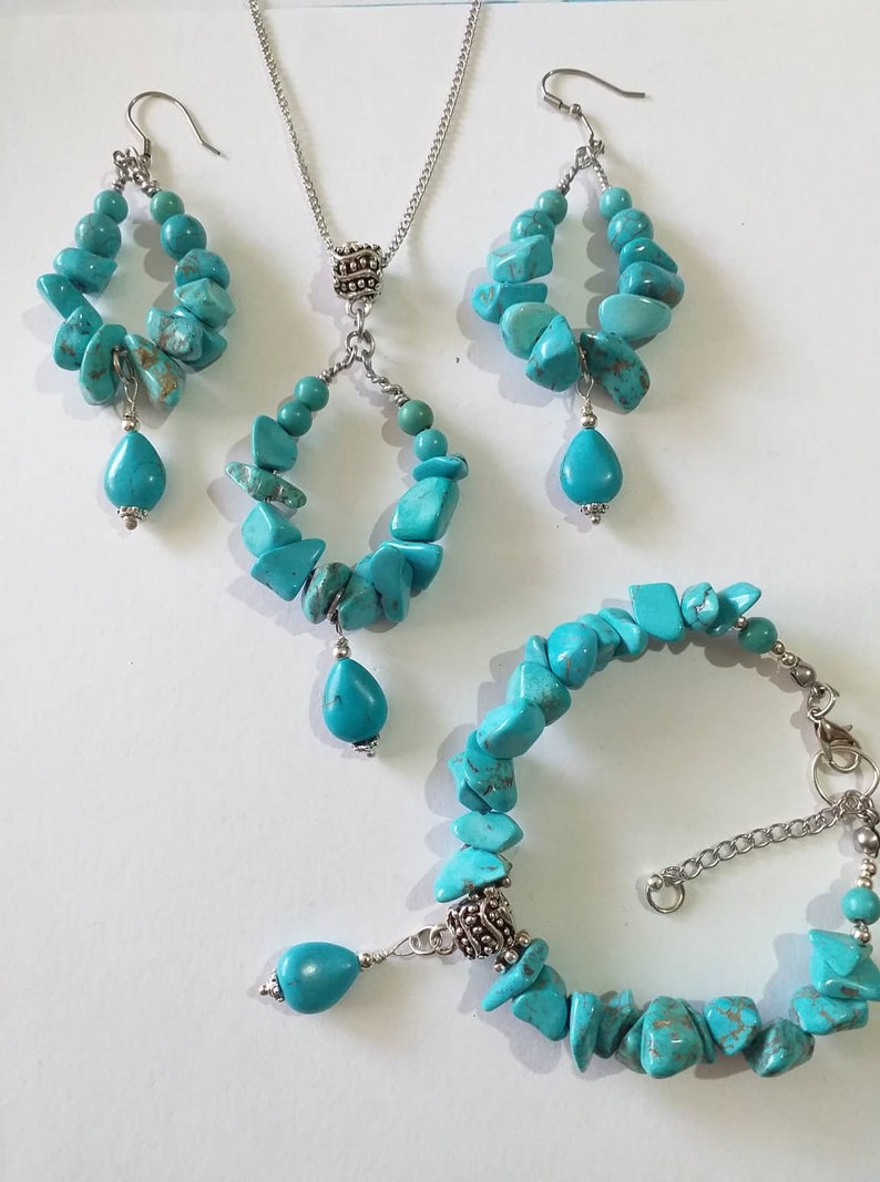 May include: Turquoise gemstone jewelry set with a necklace, earrings, and bracelet. The necklace and earrings feature a teardrop-shaped pendant and a circular design. The bracelet is made of turquoise stones and silver.