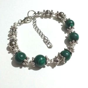 May include: A silver bracelet with green malachite beads and silver accents.