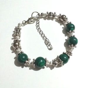 May include: A silver bracelet with green malachite beads and silver accents.