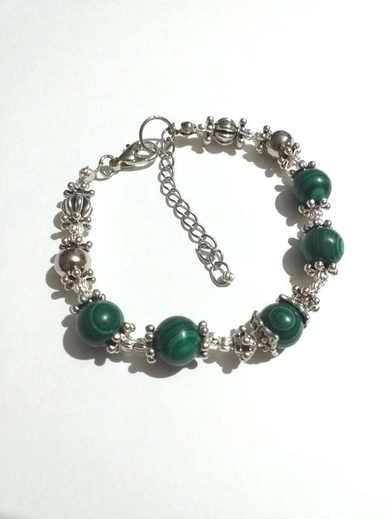 May include: A silver bracelet with green malachite beads and silver accents.