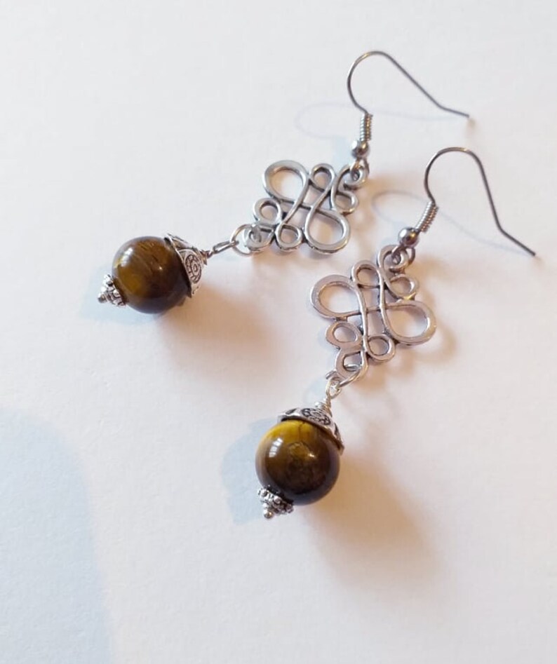 May include: A pair of silver earrings with a knotted design and a round tiger's eye stone pendant.