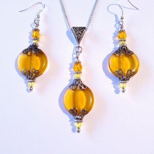 May include: A silver necklace and earrings set with amber glass beads and silver filigree accents.