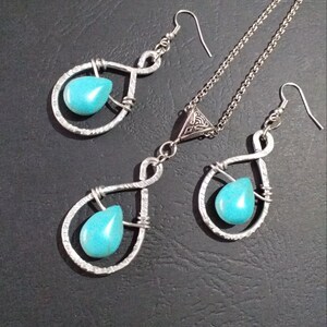 K&ouml;nnte beinhalten: Ein silbernes Halsketten- und Ohrring-Set mit t&uuml;rkisfarbenen Tr&auml;nensteinen. Die Halskette hat einen dreieckigen Anh&auml;nger mit einem keltischen Knotendesign. Die Ohrringe sind im H&auml;nge-Stil mit einem tropfenf&ouml;rmigen Stein.