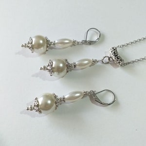 May include: A set of pearl earrings and a necklace with silver accents. The earrings have a large pearl bead and a smaller pearl bead, while the necklace has a single large pearl bead.