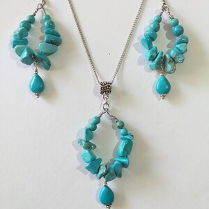 May include: A turquoise gemstone necklace and earrings set with a silver chain and a teardrop-shaped pendant.