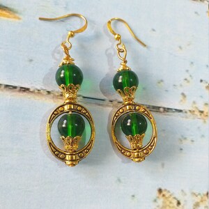 May include: Gold earrings with green glass beads and a gold filigree design.