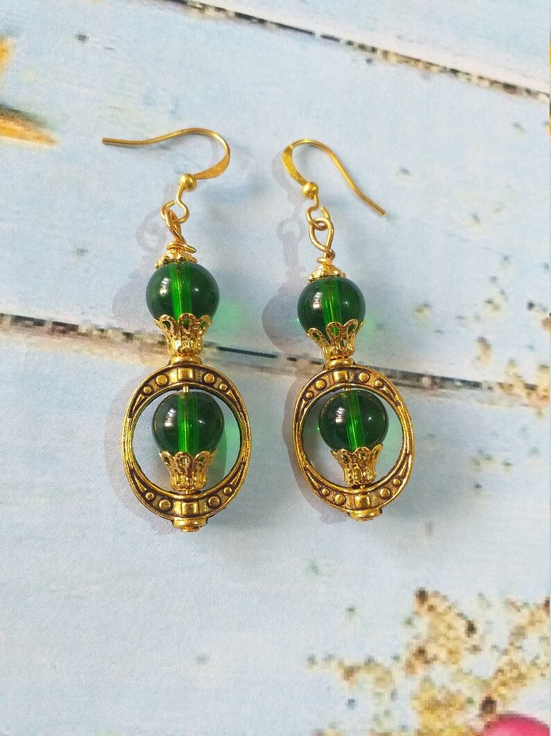 May include: Gold earrings with green glass beads and a gold filigree design.