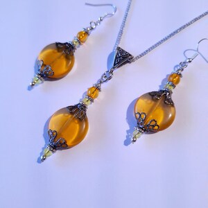 May include: A silver necklace and earrings set with amber-colored glass beads and ornate silver accents.