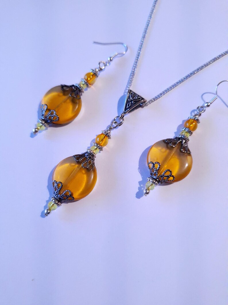May include: A silver necklace and earrings set with amber-colored glass beads and ornate silver accents.