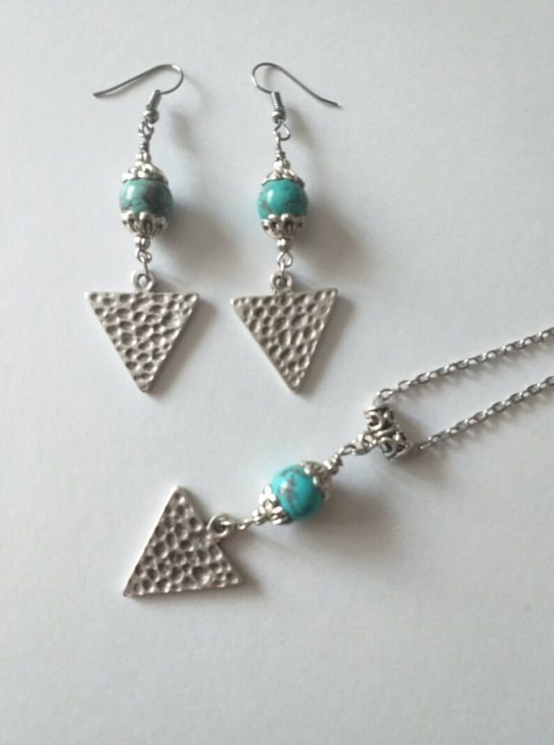 May include: A silver necklace and earrings set with turquoise beads and hammered triangle pendants.