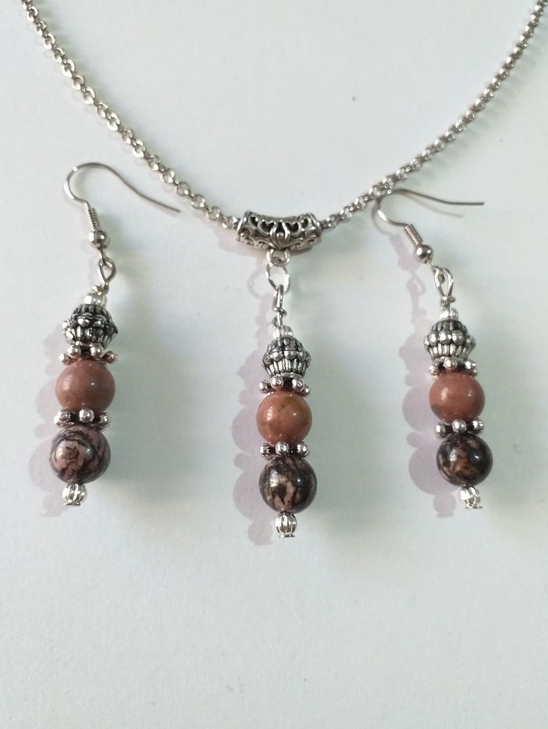 May include: A silver chain necklace with a silver pendant and three brown and black stone beads. Matching earrings with three brown and black stone beads.