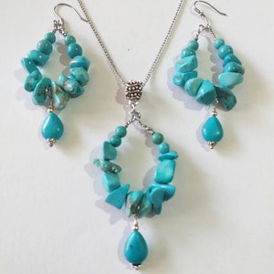May include: A turquoise gemstone necklace and earrings set with silver chain and teardrop shaped pendants.