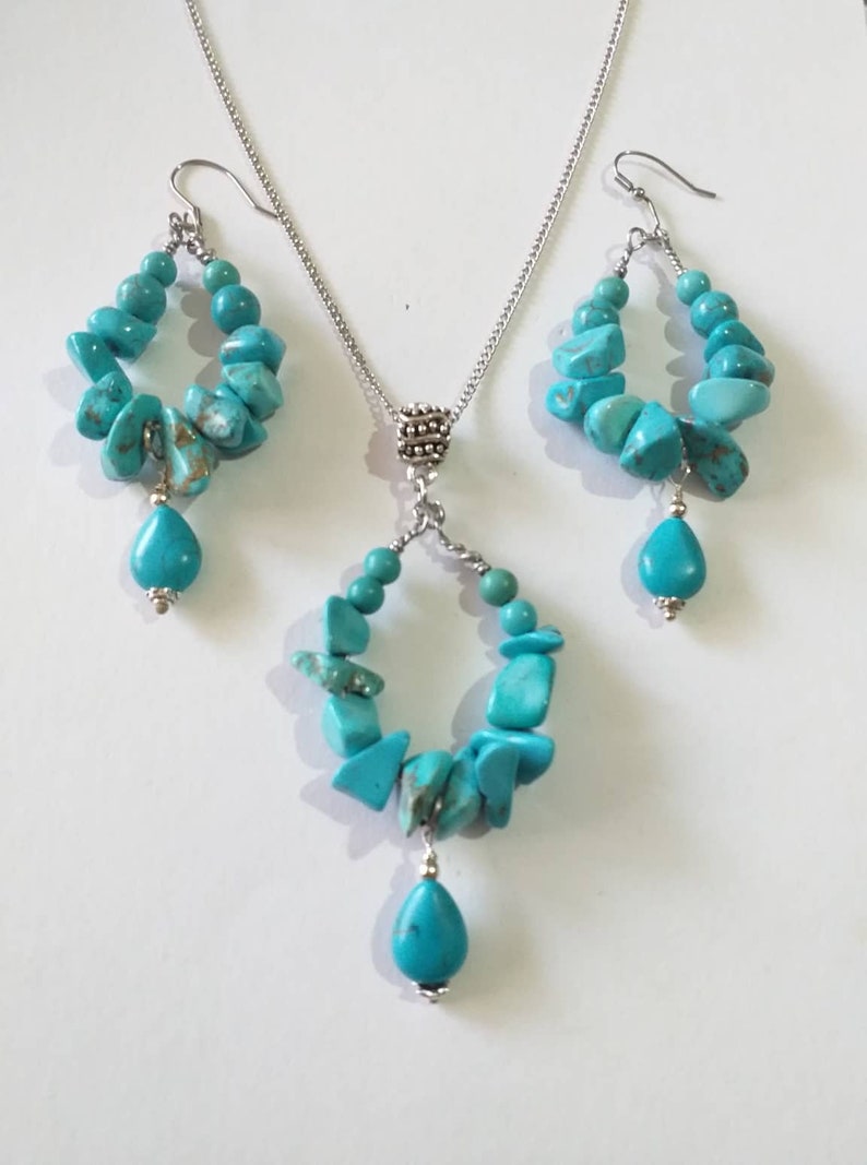 May include: A turquoise gemstone necklace and earrings set with silver chain and teardrop shaped pendants.