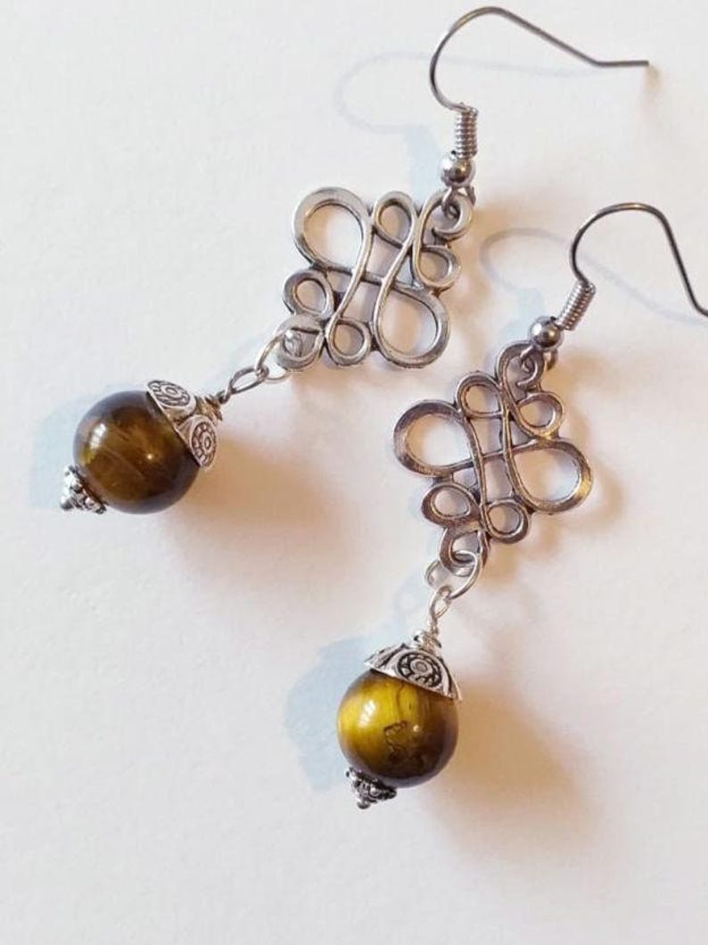 May include: A pair of silver earrings with a knotted design and a brown tiger's eye stone bead on each earring.