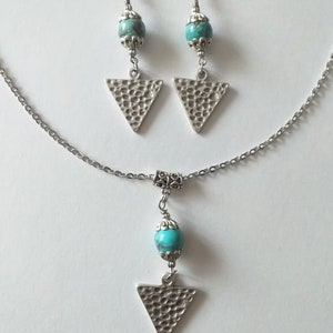 May include: A silver necklace and earrings set with turquoise beads and triangle pendants. The triangle pendants have a hammered texture.