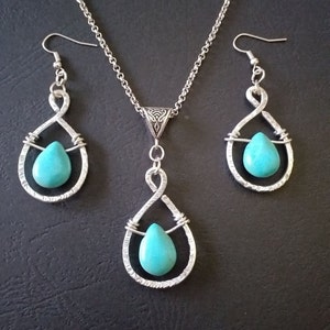 K&ouml;nnte beinhalten: Ein silbernes Halsketten- und Ohrring-Set mit t&uuml;rkisfarbenen Tr&auml;nensteinen. Halskette und Ohrringe haben ein zartes, gedrehtes Drahtdesign.