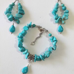May include: Turquoise gemstone jewelry set with a bracelet, a pair of earrings, and a silver charm. The bracelet and earrings feature turquoise stones in various shapes and sizes.
