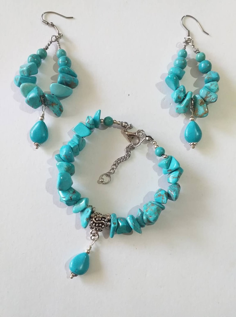 May include: Turquoise gemstone jewelry set with a bracelet, a pair of earrings, and a silver charm. The bracelet and earrings feature turquoise stones in various shapes and sizes.