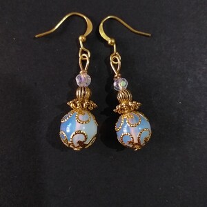 May include: A pair of gold earrings with a blue and white opal-like stone and gold filigree design.