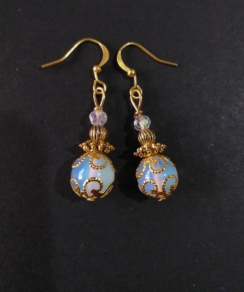 May include: A pair of gold earrings with a blue and white opal-like stone and gold filigree design.