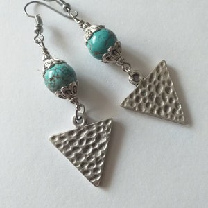May include: A pair of silver earrings with turquoise beads and triangle pendants. The triangles have a hammered texture.