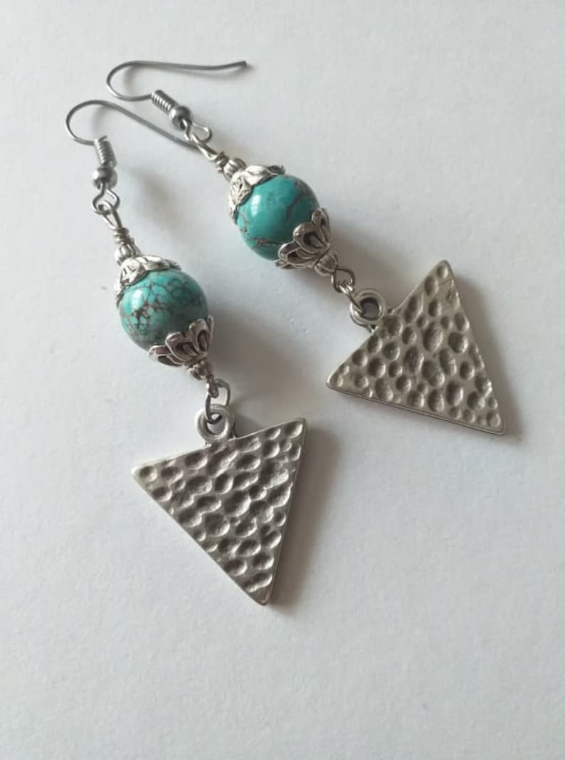 May include: A pair of silver earrings with turquoise beads and triangle pendants. The triangles have a hammered texture.