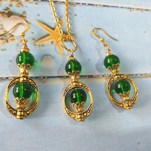 May include: A gold necklace and earrings set with green glass beads and ornate gold accents.