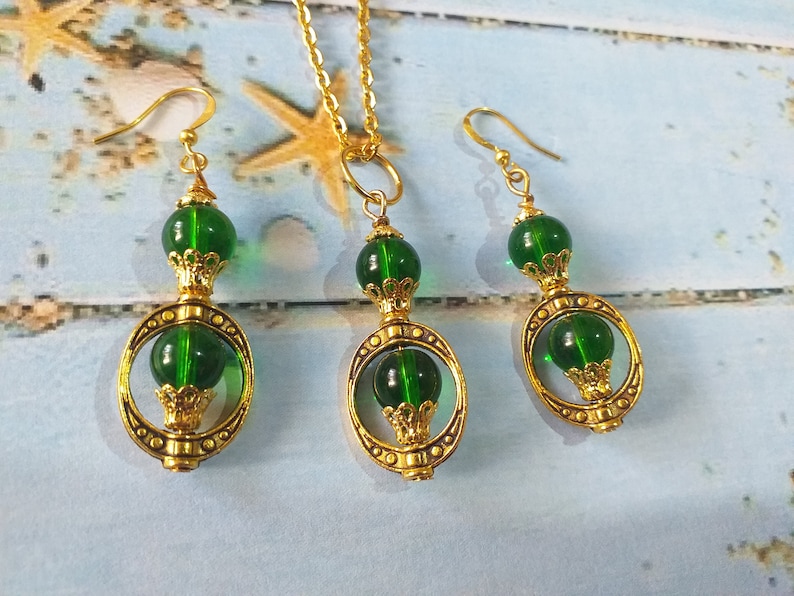 May include: A gold necklace and earrings set with green glass beads and ornate gold accents.