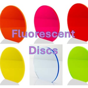 May include: Six fluorescent discs in vibrant colours: orange, hot pink, red, yellow, clear with blue trim, and green. Each disc is round and mounted on a small white base. The words "Fluorescent" and "Discs" are printed on the image.