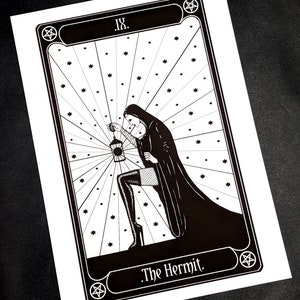 May include: Black and white illustration of The Hermit tarot card. The card features a woman in a hooded robe holding a lantern, with a pentagram in the corner.
