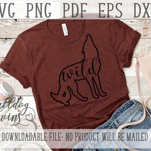 May include: A brown t-shirt with a black silhouette of a wolf with the word "wild" written inside the silhouette. The t-shirt is laying on a wooden surface with a pair of jeans and a purse.