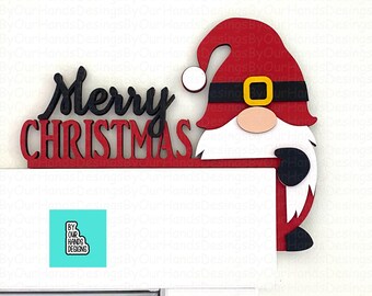 May include: Red and white wooden Christmas gnome holding a sign that says "Merry Christmas".